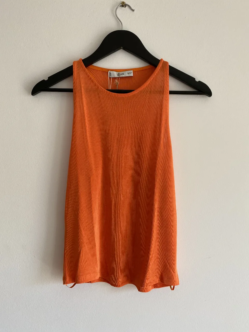 Musculosa naranja de tejido ligero y fresco, ideal para el verano. Diseño simple y moderno, perfecta para combinar con jeans o shorts.