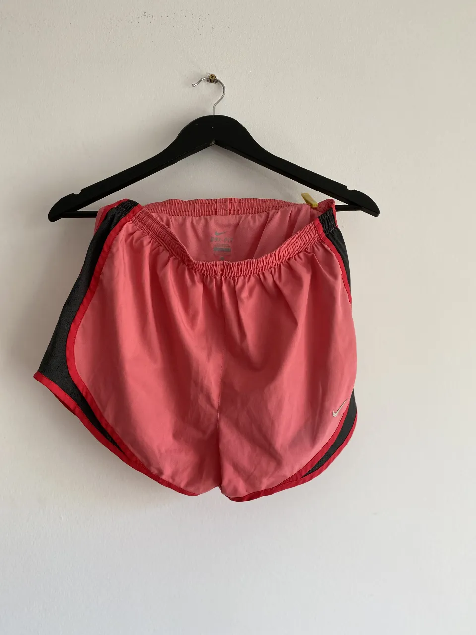 Short deportivo Nike de mujer, color rosa con detalles en gris y rojo. Ideal para running y entrenamientos.