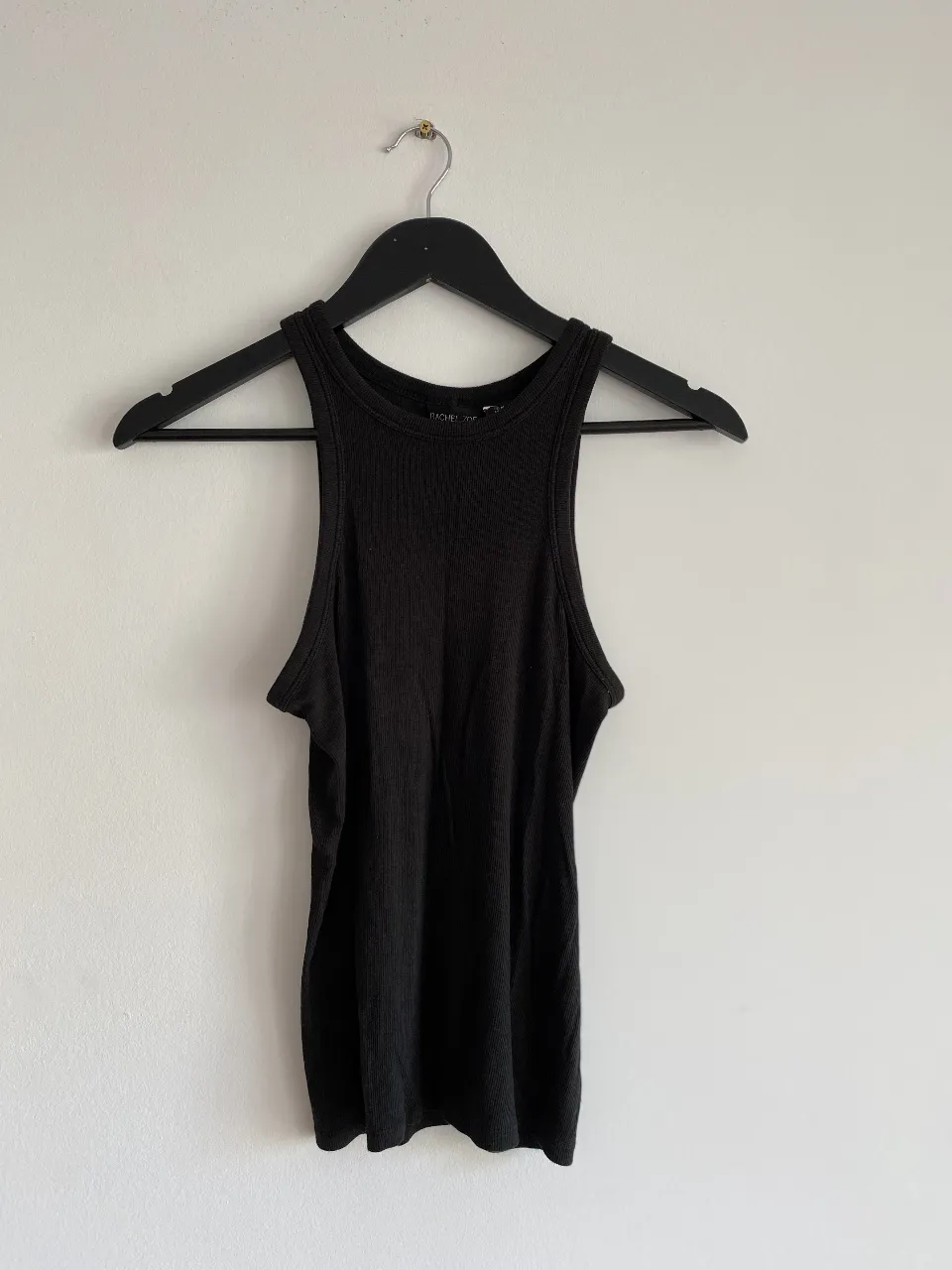 Musculosa negra de tejido acanalado, ideal para un look casual y cómodo. Perfecta para combinar con jeans o shorts.