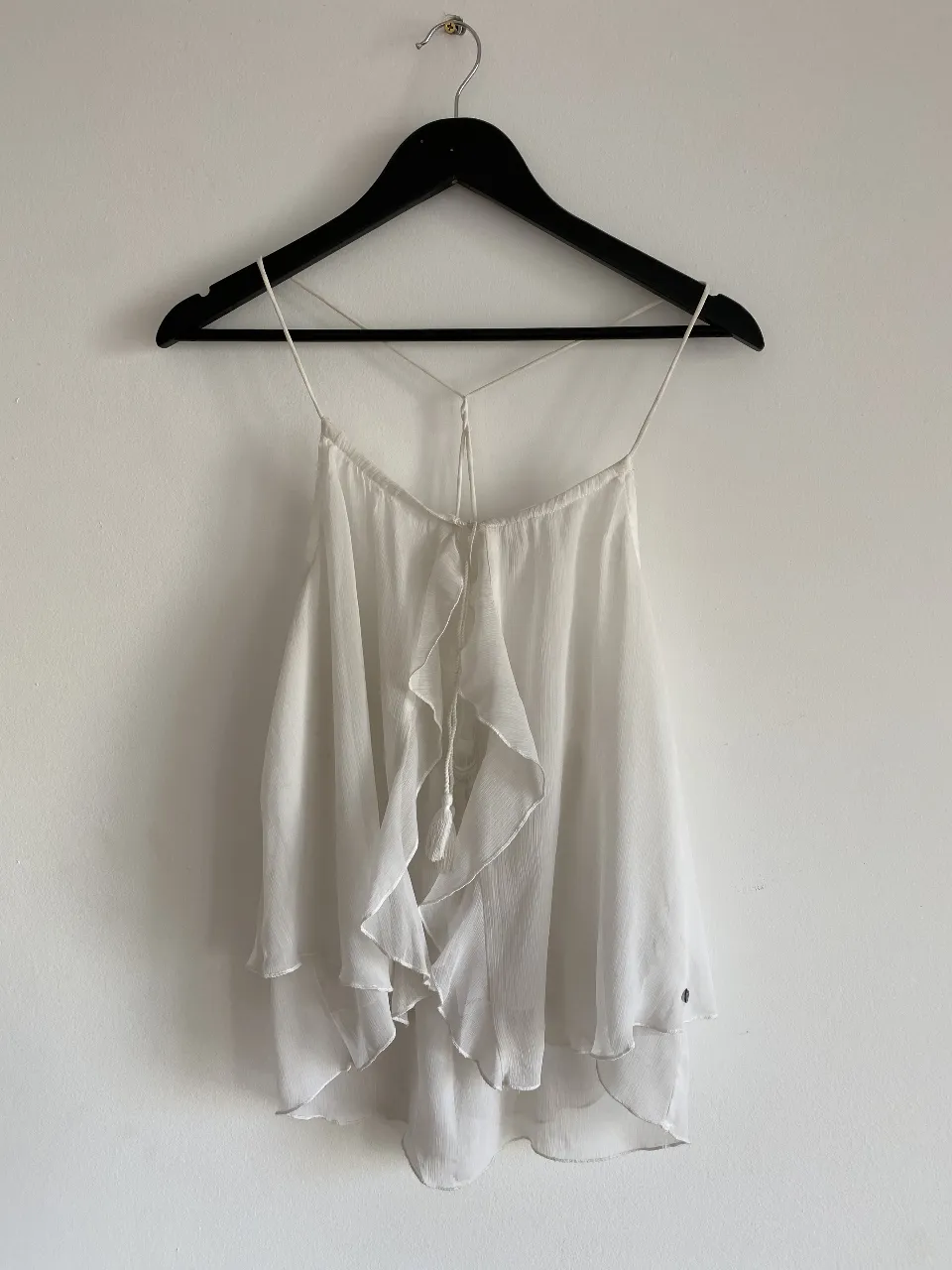 Top blanco con volados y tiras finas. Ideal para un look fresco y femenino.