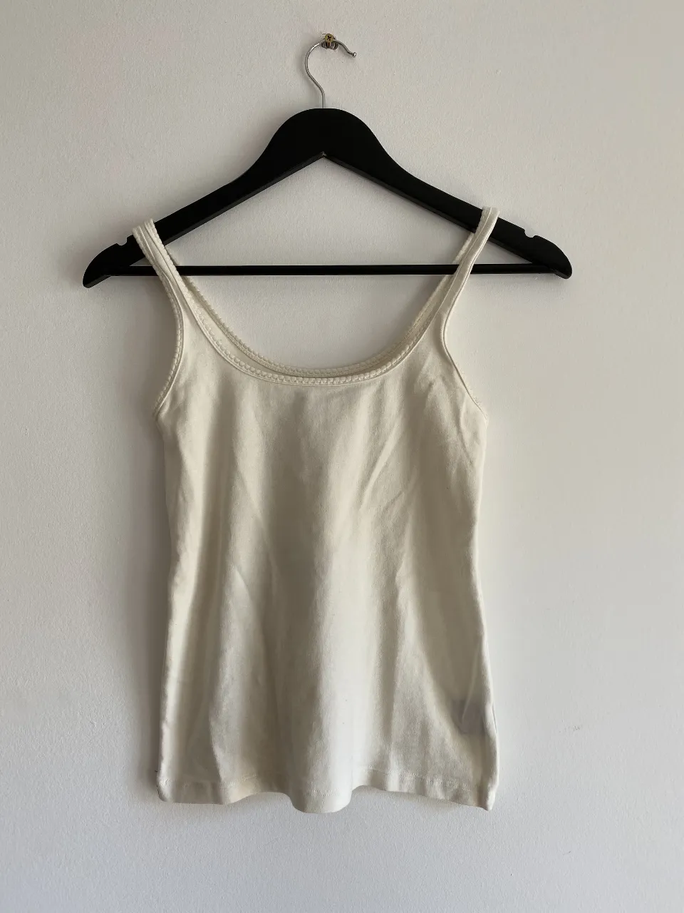 Musculosa de algodón color blanco, ideal para usar debajo de otras prendas o como top básico. Cuello redondo y tirantes finos.