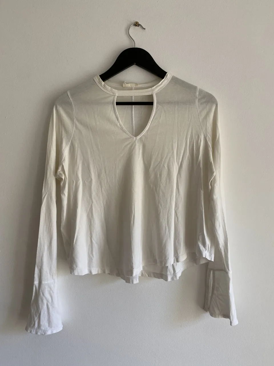 Blusa blanca de manga larga con detalle de abertura en el cuello. Ideal para un look casual y elegante.