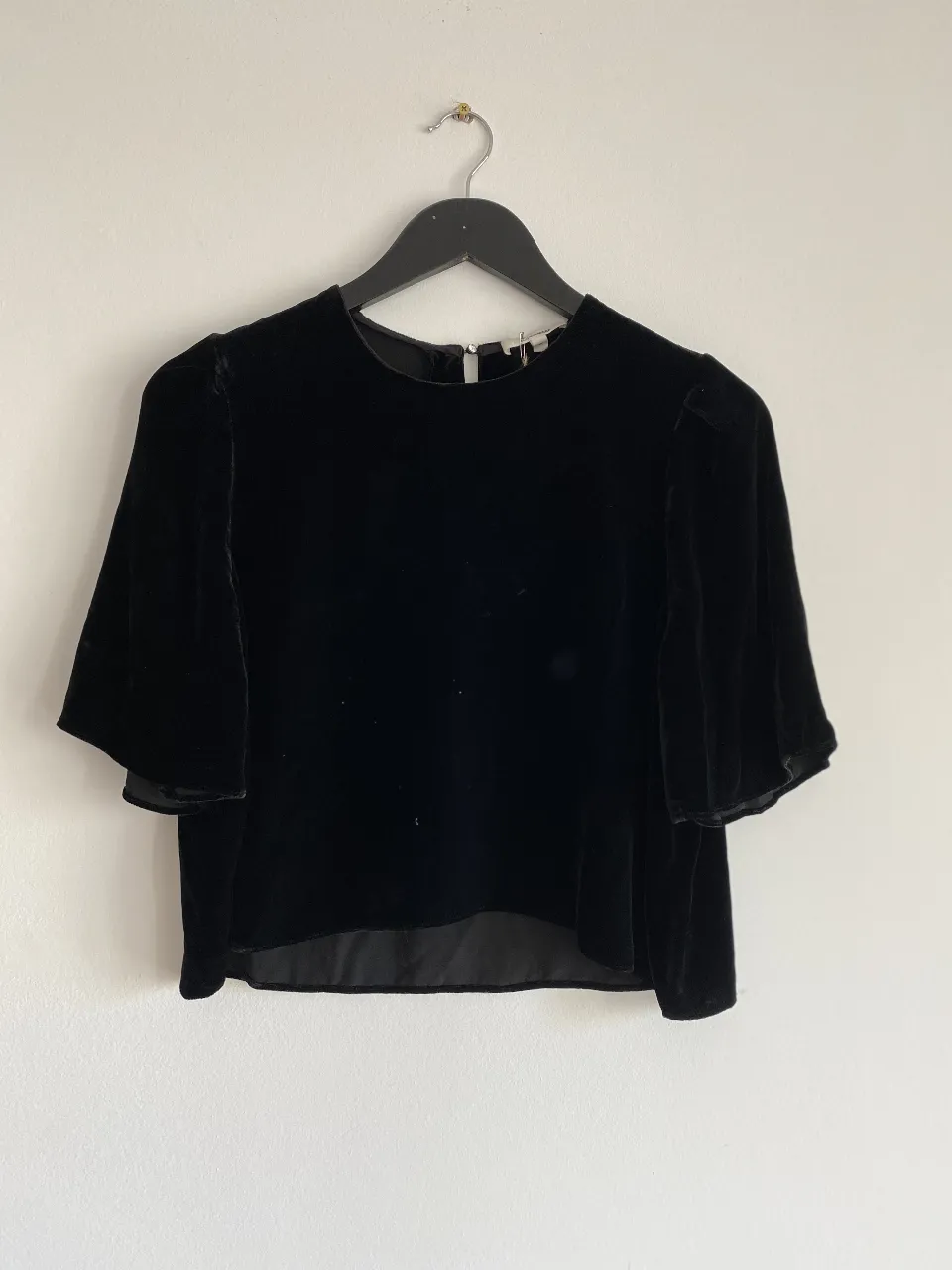 Blusa de terciopelo negro con mangas cortas abullonadas. Ideal para un look elegante y sofisticado.