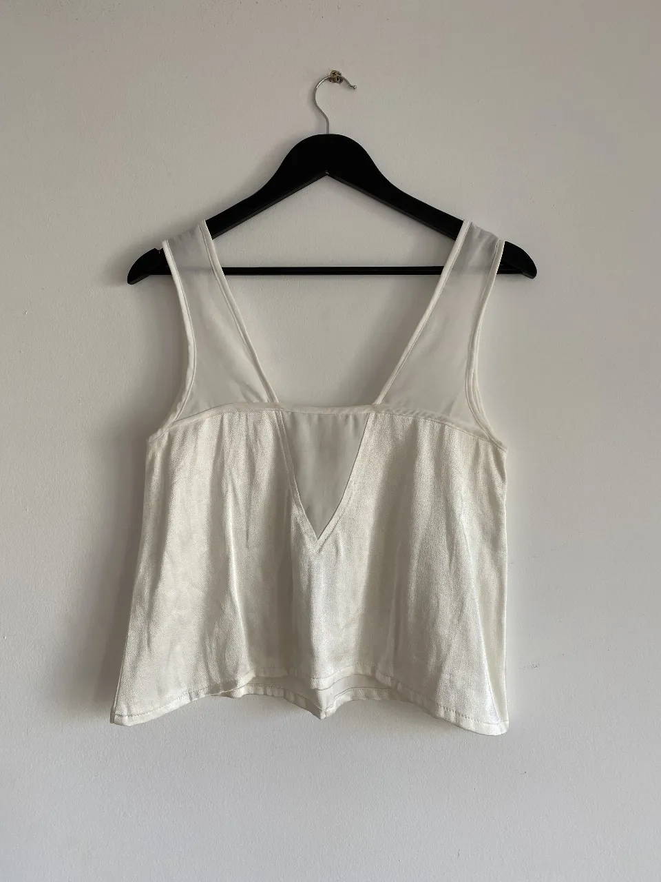 Top blanco con escote en V y detalles de transparencia. Ideal para un look elegante y moderno.