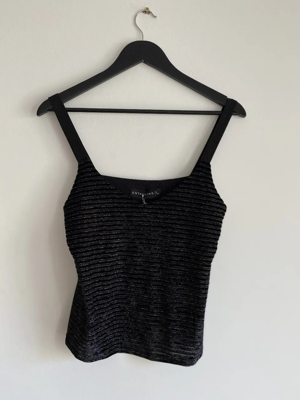 Top negro con brillo, ideal para una salida nocturna. Diseño con tiras finas y detalle de textura horizontal.