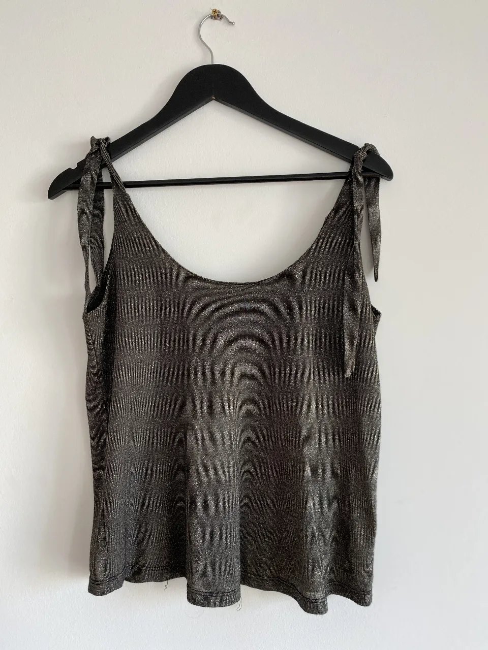 Top de mujer con tirantes finos y lazos en los hombros. Confeccionado en tela brillante, ideal para un look de fiesta o salida.