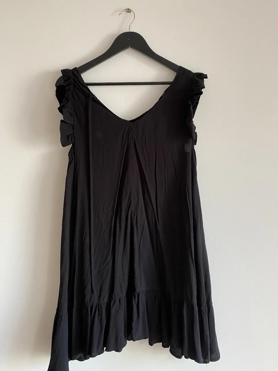 Vestido negro corto con volados en mangas y falda. Ideal para un look fresco y casual.