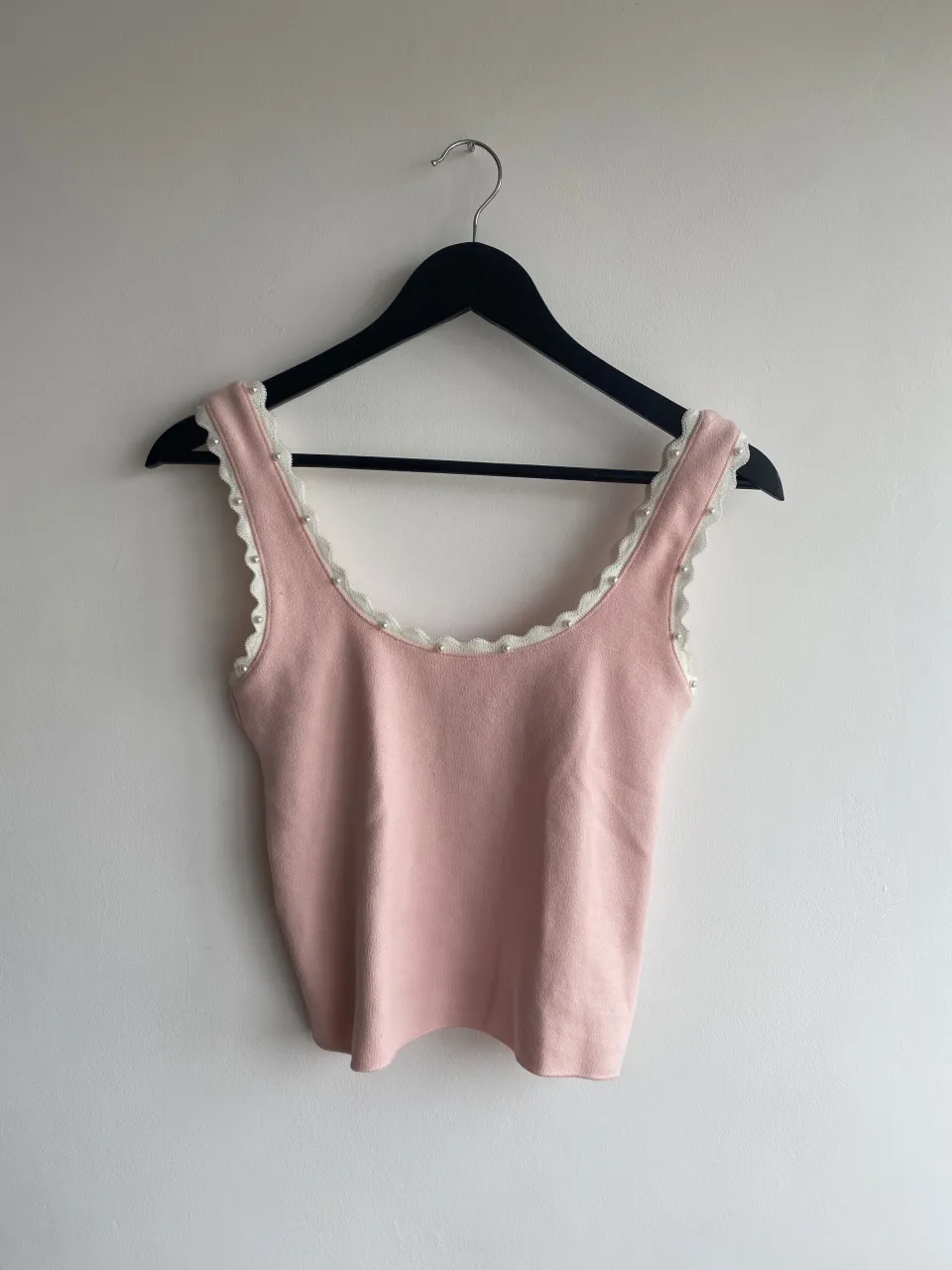 Top rosa de tejido suave con detalles de perlitas y borde de encaje blanco. Ideal para un look delicado y femenino.