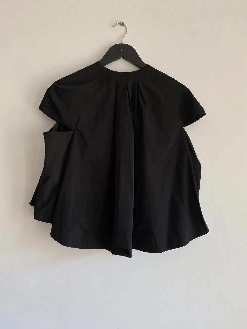 Blusa negra con diseño original, con mangas cortas y detalles únicos. Ideal para un look moderno y sofisticado.
