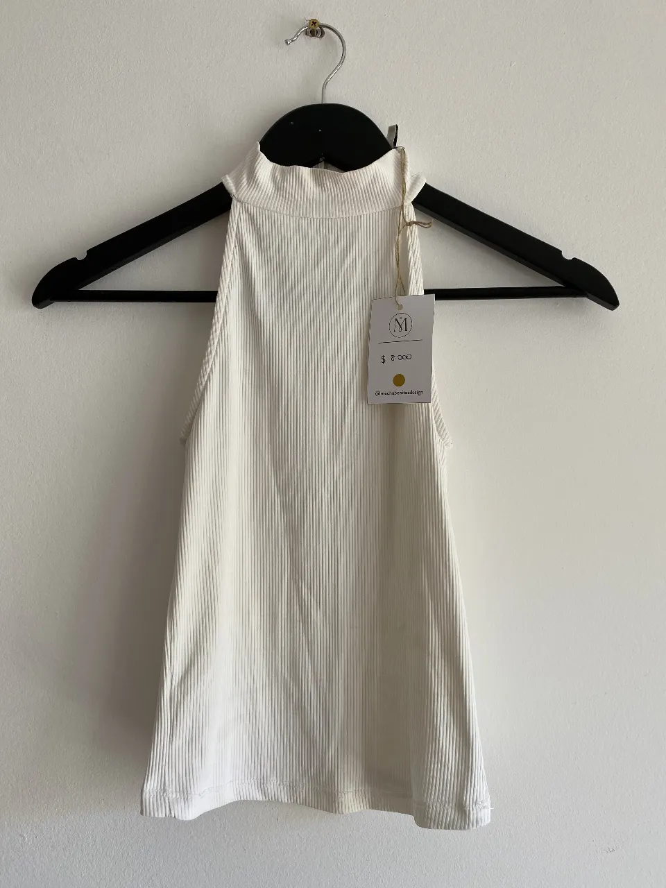 Top blanco de cuello alto y corte ajustado. Ideal para combinar con jeans o pantalones de vestir. Perfecto para un look casual o para salir.