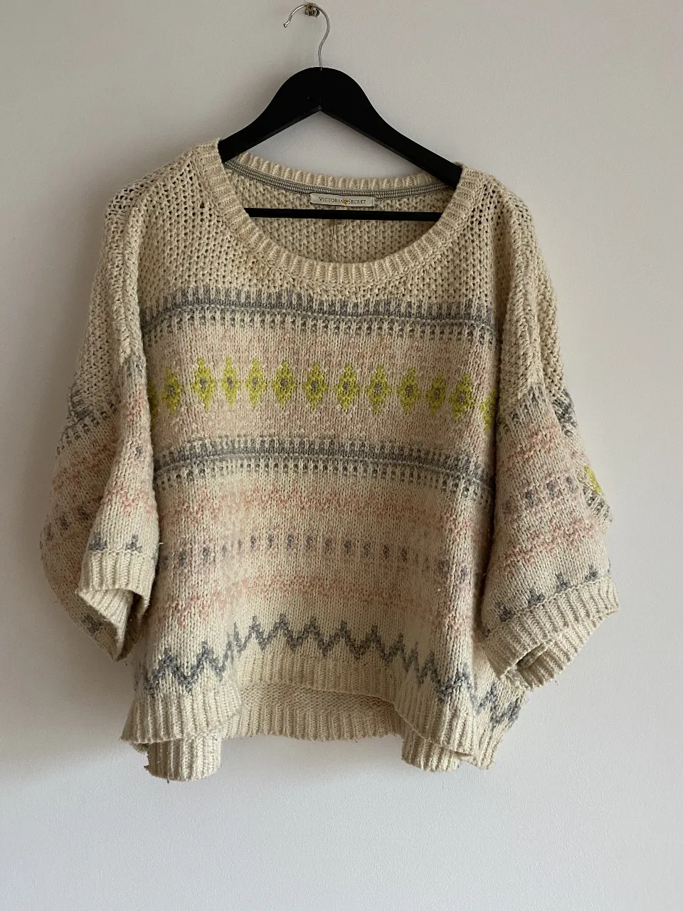 Sweater de lana tejido con diseño geométrico en tonos neutros y detalles en amarillo. Ideal para un look casual y abrigado.