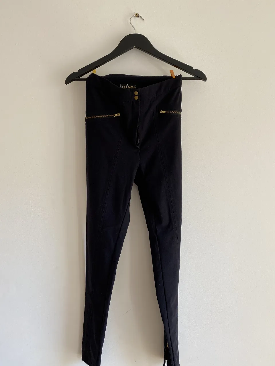Pantalón negro de vestir con cierre y detalles dorados. Ideal para un look elegante y sofisticado.