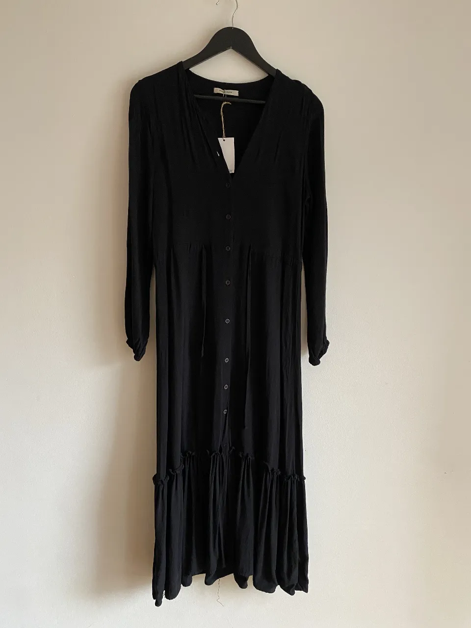 Vestido largo negro con botones y volados en el ruedo. Ideal para un look elegante y cómodo.