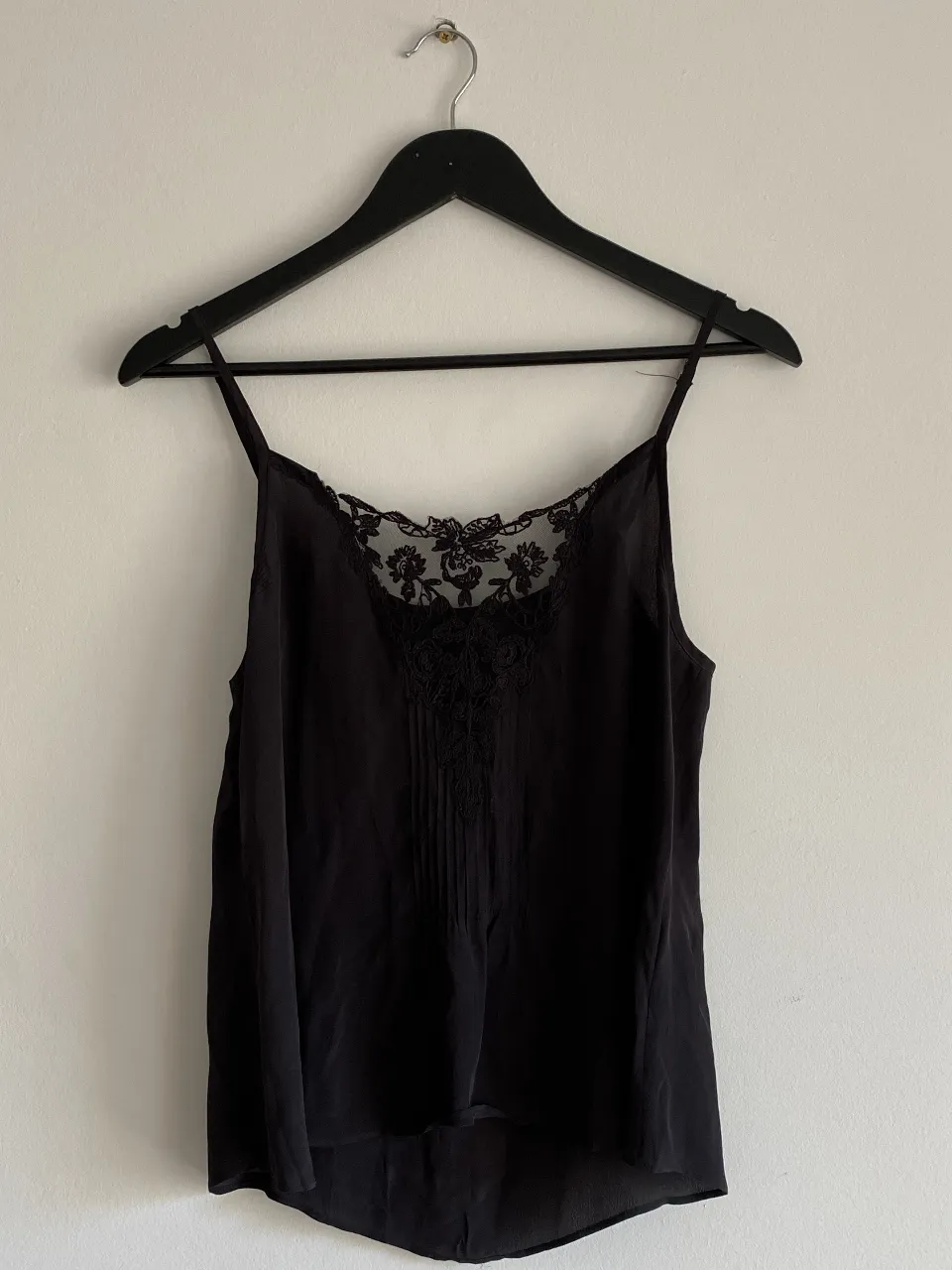 Top negro con detalles de encaje en el escote y la parte superior. Ideal para una salida elegante o para combinar con diferentes outfits. Conjunto con la pollera de encaje en dos agua, haciendo juego con el top