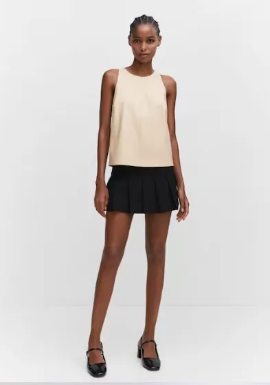 Top de mujer en color crudo, sin mangas y con diseño minimalista. Ideal para combinar con faldas o pantalones de cintura alta. Perfecto para un look elegante y moderno.