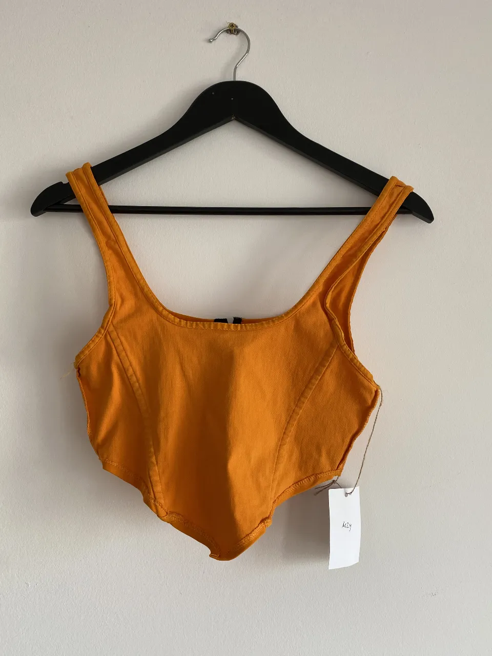 Top naranja con escote cuadrado y detalle de cierre frontal. Ideal para un look moderno y audaz.