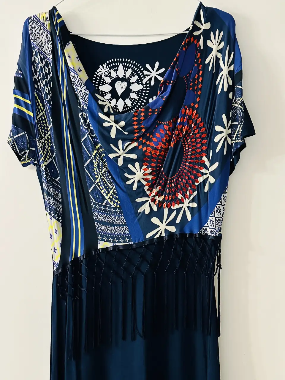 Vestido midi de la marca Desigual, con estampado en la parte superior y falda lisa. Posee detalles de flecos en la cintura y un diseño único.