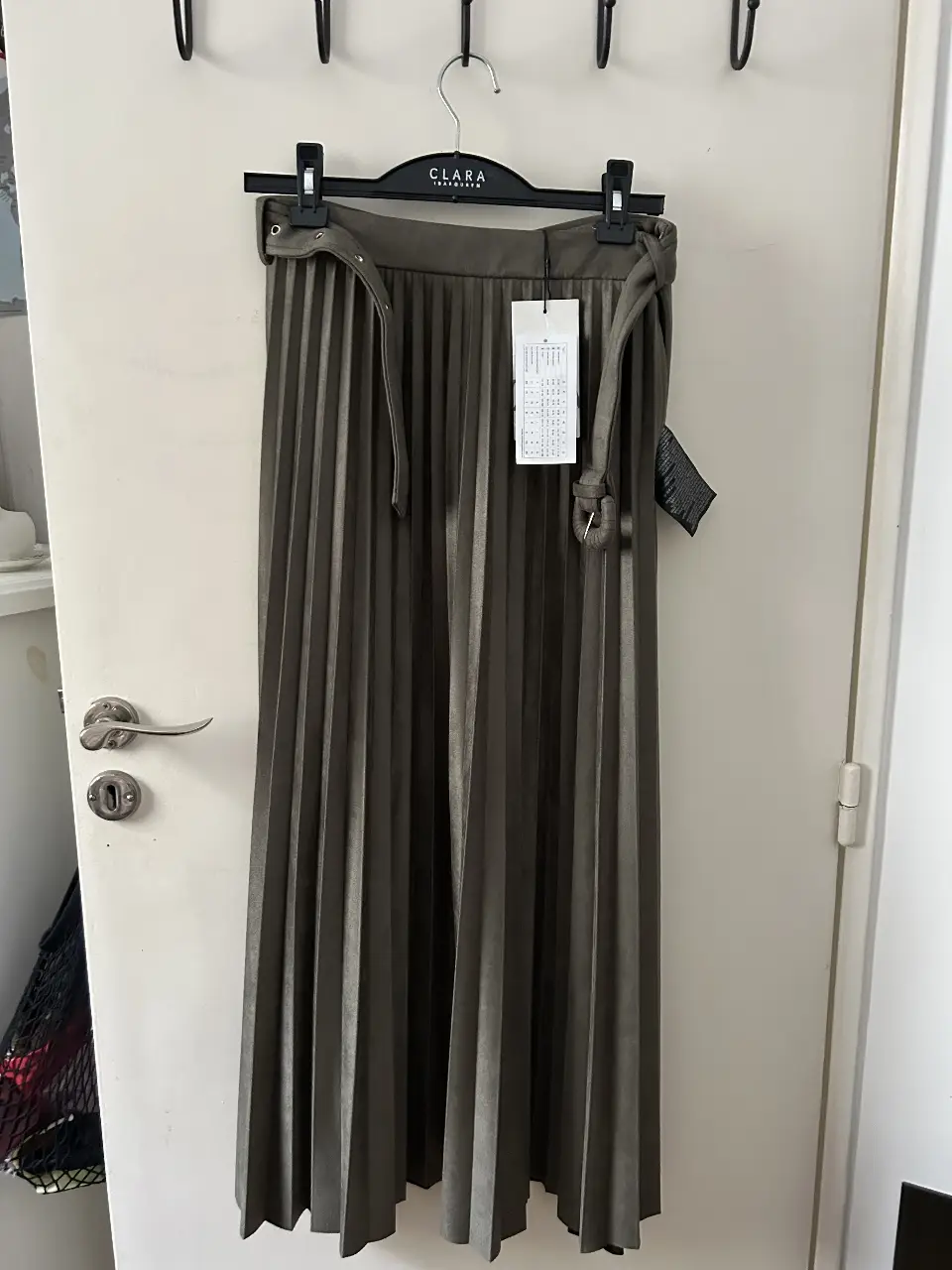 Pollera midi plisada de color verde oscuro con cinturón a juego. Ideal para un look elegante y sofisticado.