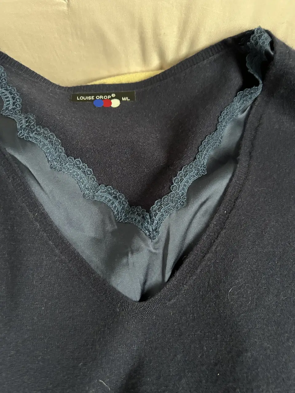 Sweater azul marino con detalle de encaje en el cuello en V y una capa de satén superpuesta. Ideal para un look elegante y sofisticado.