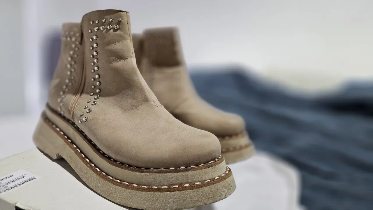 Botas de cuero color tiza con tachas plateadas y cierre lateral. Suela track con pespunte a la vista.