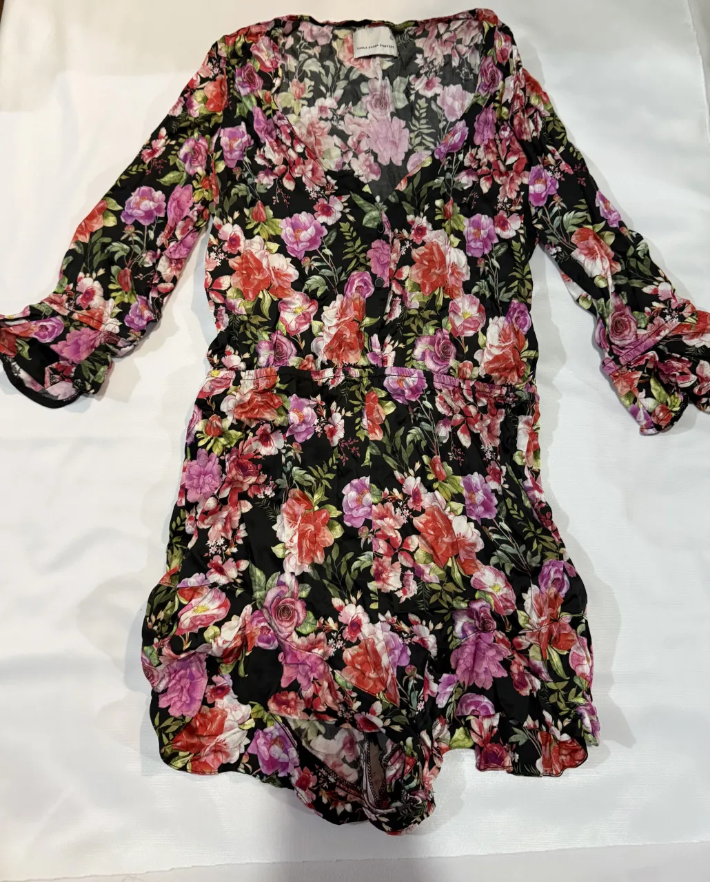 Vestido corto estampado floral, con mangas largas acampanadas y detalle de botones en el frente. Ideal para un look casual y femenino.