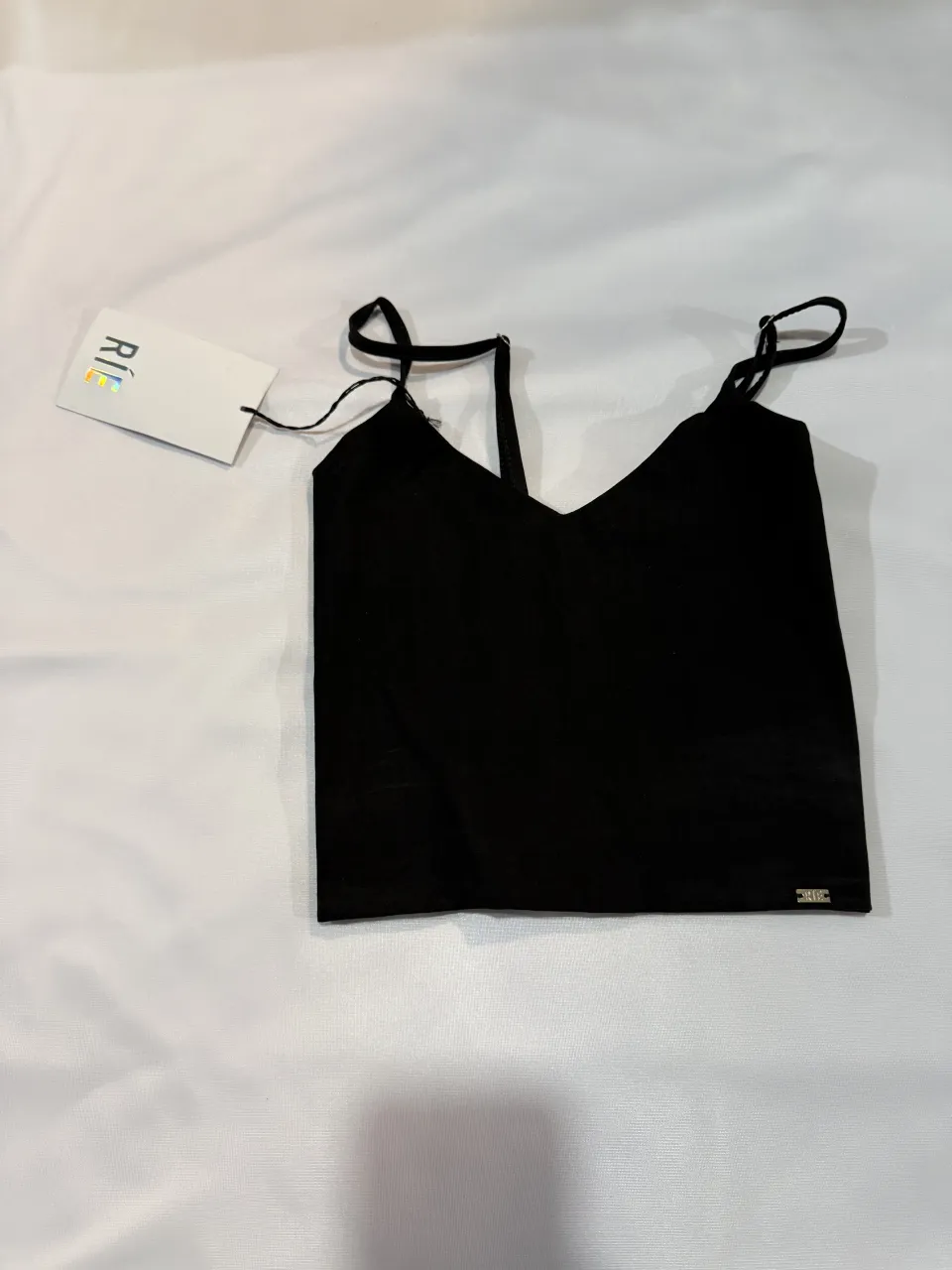 Top negro con tiras finas y detalle fruncido en la espalda. Ideal para un look canchero y moderno.