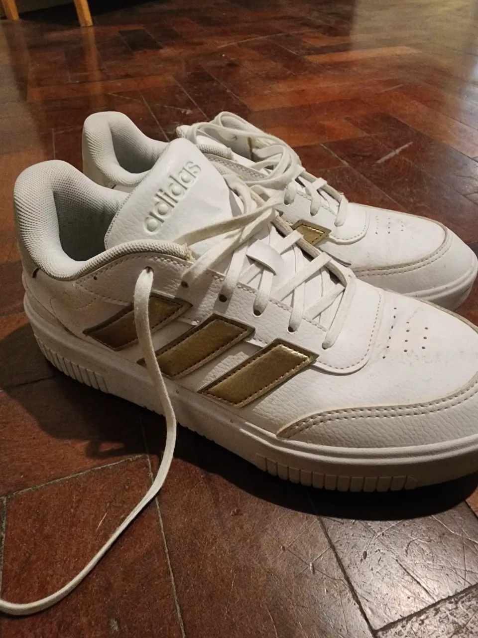 Zapatillas Adidas blancas con detalles dorados. Ideales para un look casual y cómodo. Perfectas para el día a día.