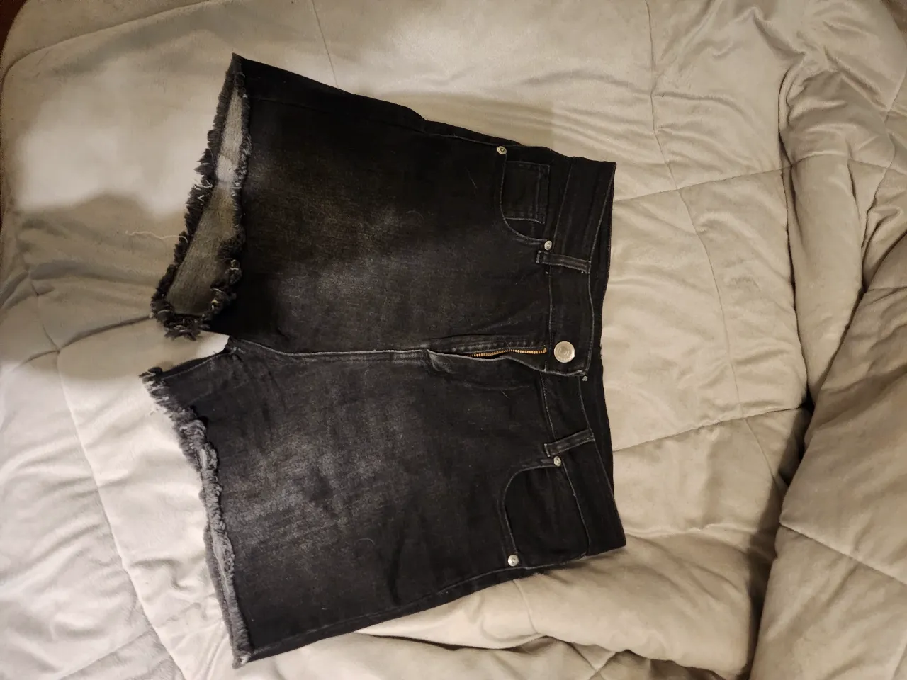 Short de jean negro con detalles desflecados en los bordes. Ideal para un look casual y moderno.