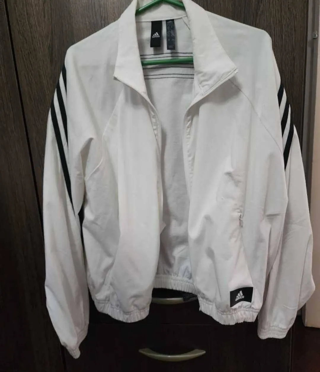 Campera deportiva Adidas blanca con detalles en negro. Ideal para entrenar o usar en el día a día. Posee cierre y las clásicas tres tiras en las mangas.