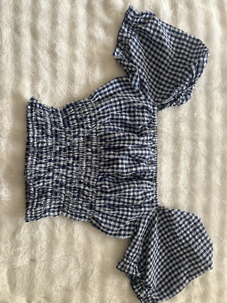 Remera corta de cuadros escoceses en azul y blanco. Posee fruncido en el torso y mangas cortas con volados.