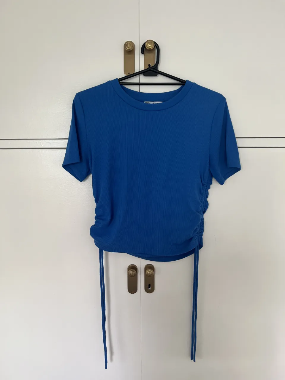 Remera azul de manga corta con fruncido lateral y cordones ajustables.