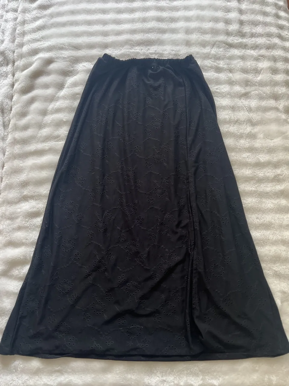 Pollera larga negra con detalles de bordado y abertura laterales.