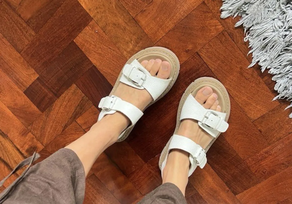 Sandalias blancas con dos tiras y hebillas metálicas. Suela gruesa.