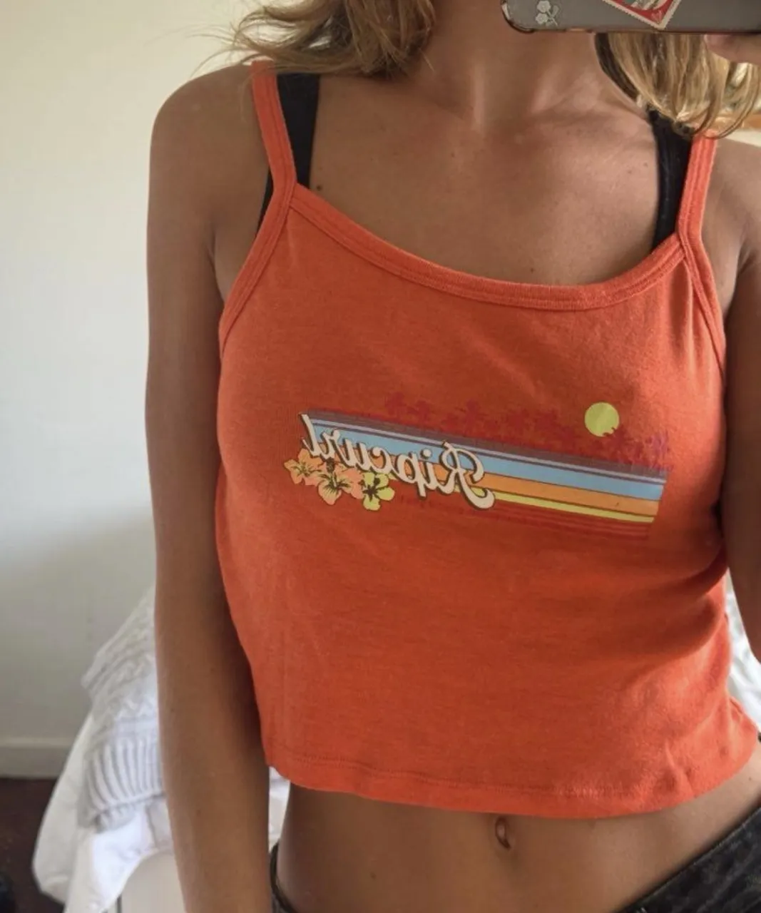 Musculosa crop naranja con estampa de flores y palmeras, y la inscripción "Ripcurl".