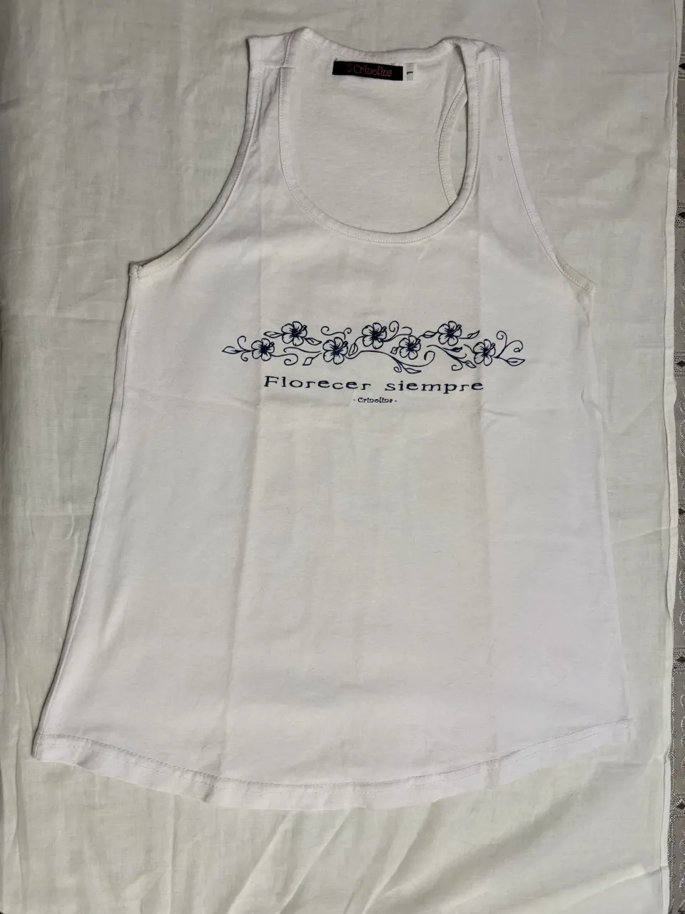 Musculosa blanca con estampa floral y frase "Florecer siempre". Ideal para un look casual y fresco.