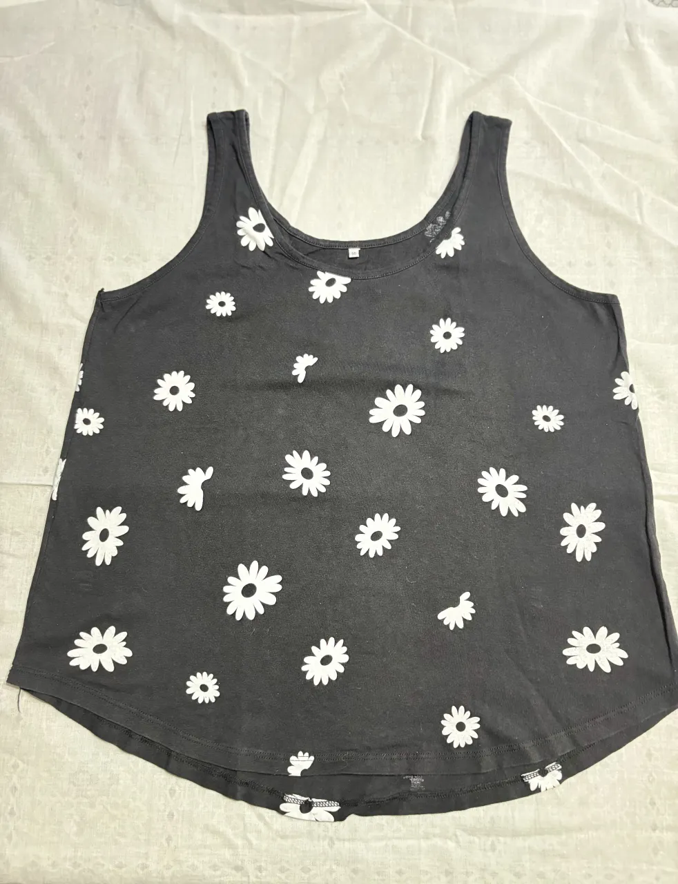 Musculosa negra con estampa de flores blancas estilo margaritas. Ideal para un look casual y fresco.