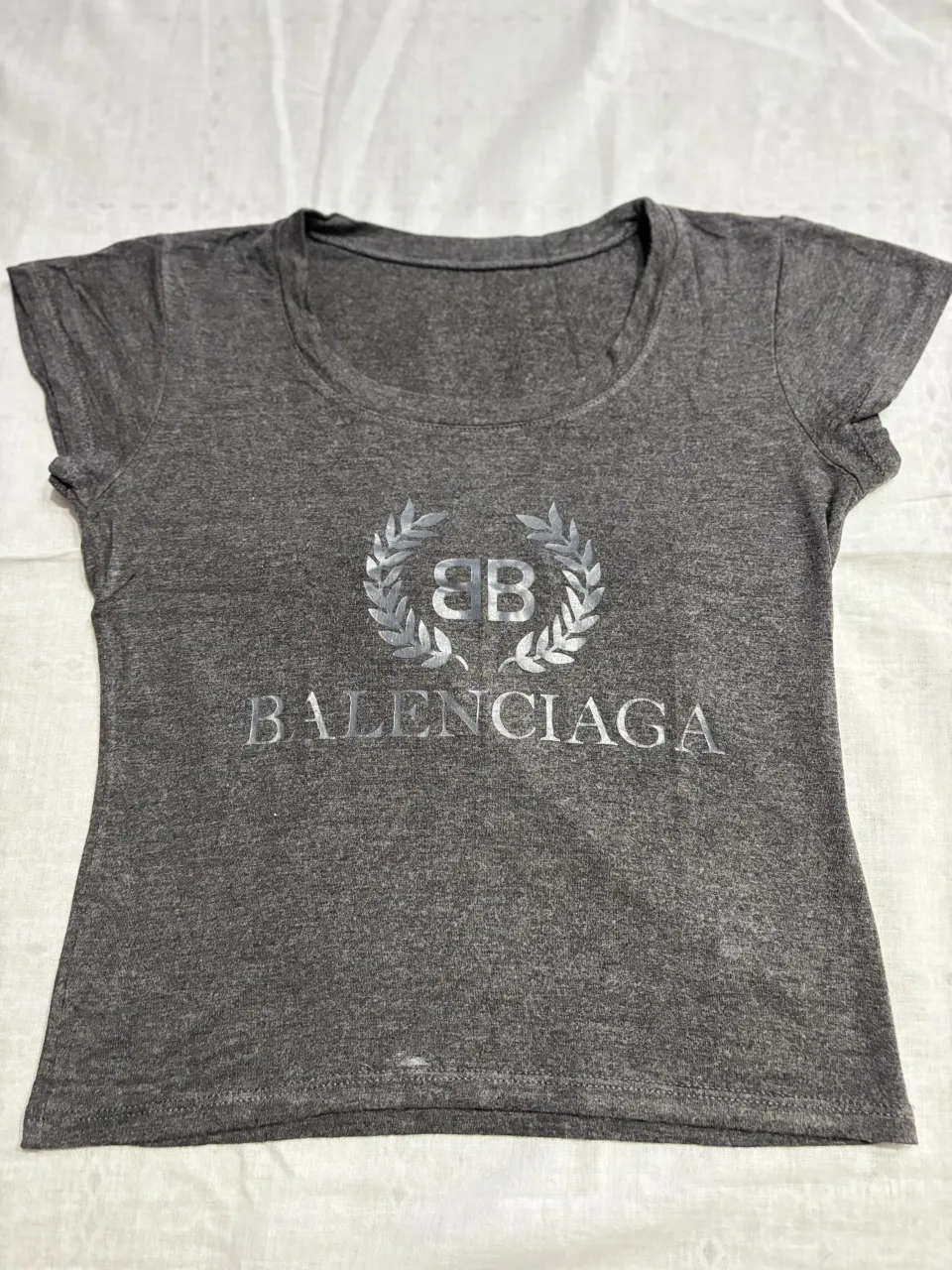 Remera gris de manga corta con el logo de Balenciaga estampado en plateado. Un clásico que no puede faltar en tu guardarropa.
