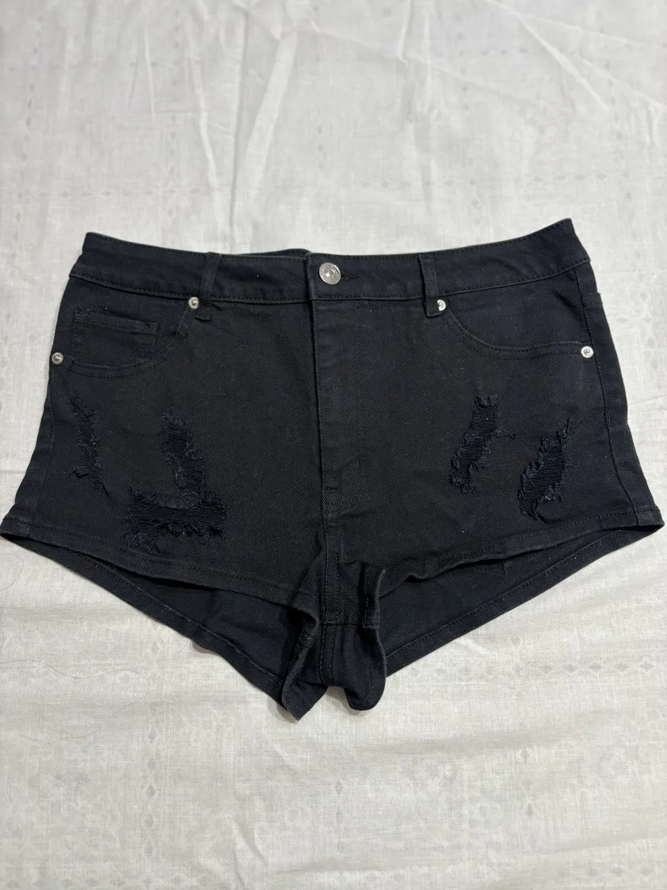Shorts de jean negros con roturas, tiro alto. Ideales para un look canchero y moderno.