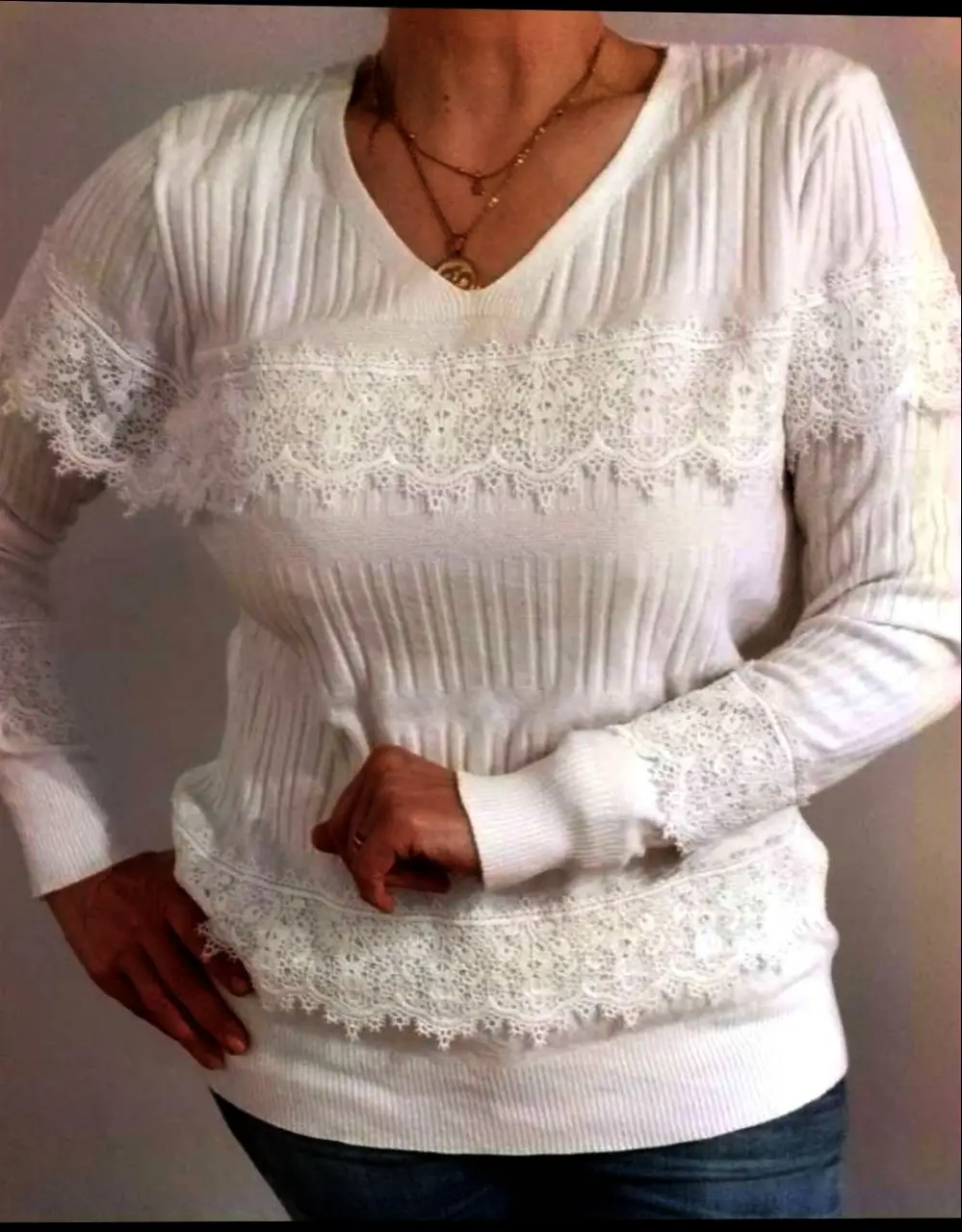 Sueter blanco con detalles de encaje en el pecho, mangas y borde inferior. Ideal para un look elegante y femenino.