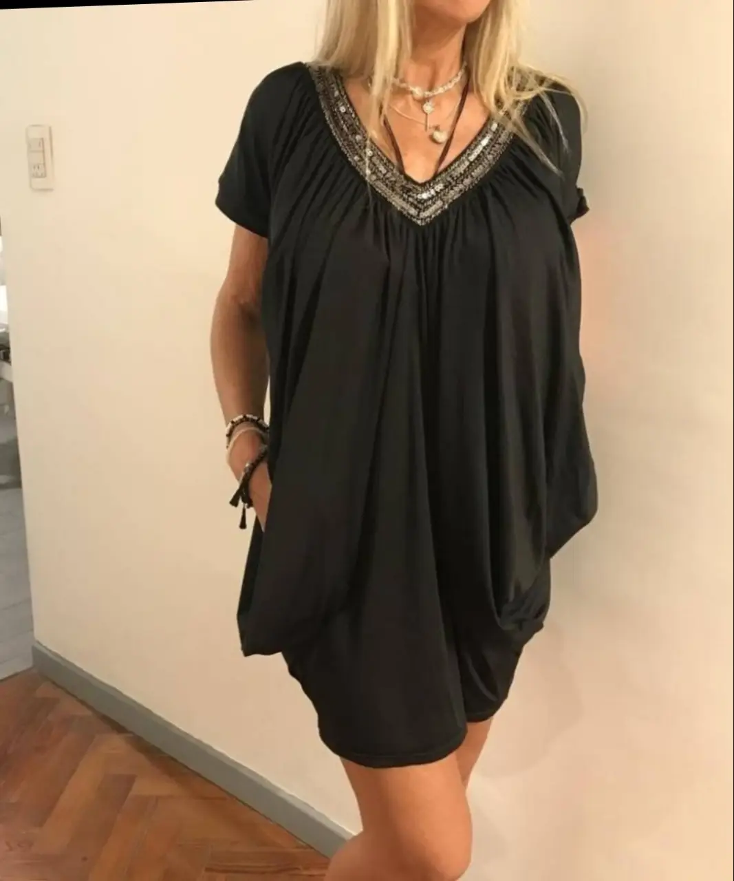 Vestido negro con cuello en V adornado con detalles plateados. Diseño holgado y mangas cortas, ideal para un look moderno y cómodo. Importado ,modelo murciélago ,con bolsillos y detalle de  galón con lentejuelas y canutillo en cuello 