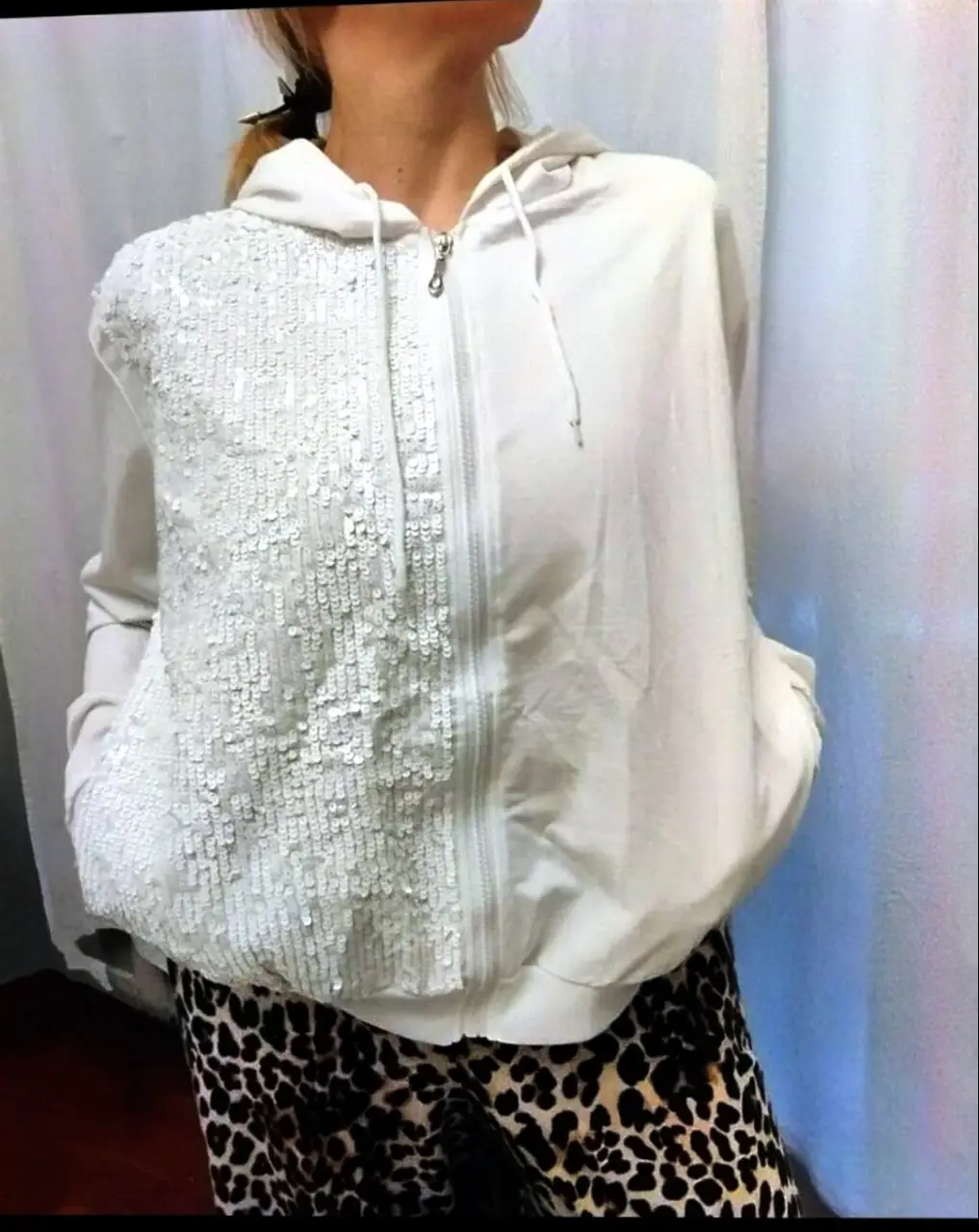 Buzo blanco con cierre y capucha. La parte delantera tiene lentejuelas. Ideal para un look casual y canchero.