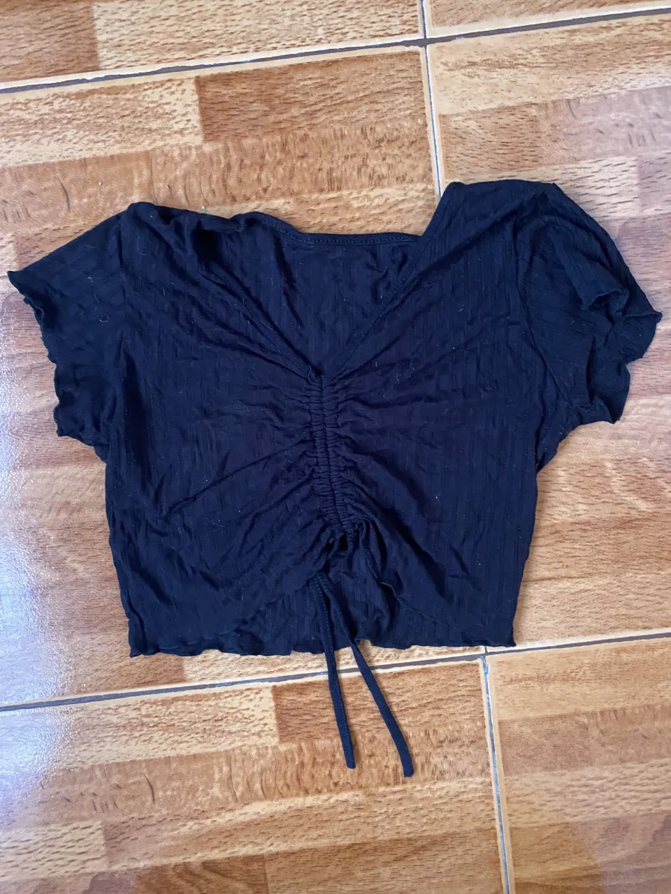 Top negro con fruncido y cordón ajustable en el frente. Manga corta y escote en V. Ideal para un look casual y moderno.