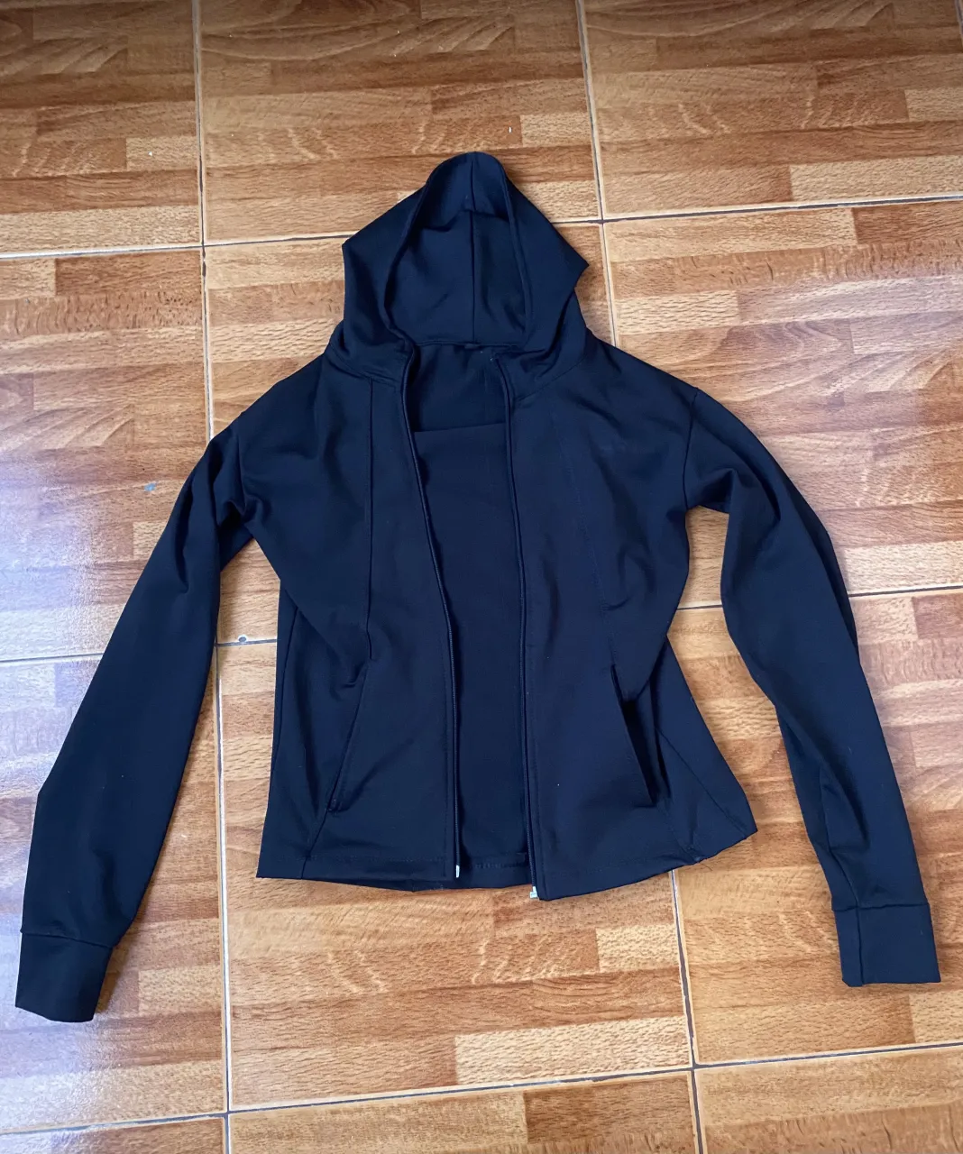 Buzo/campera negro con capucha sin cierre. Ideal para entrenamientos o para un look casual y cómodo. Mangas largas y bolsillos frontales. 