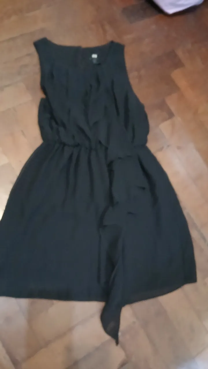 Vestido negro corto, sin mangas, con detalles de volados y cintura elastizada. Ideal para una salida o fiesta.