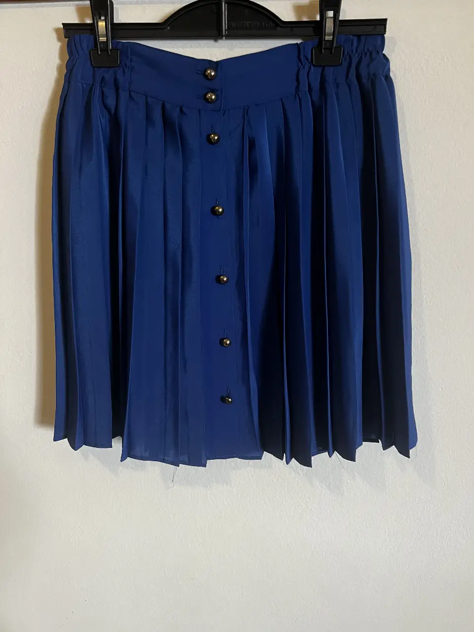 Pollera plisada azul con botones dorados. Ideal para un look elegante y sofisticado.