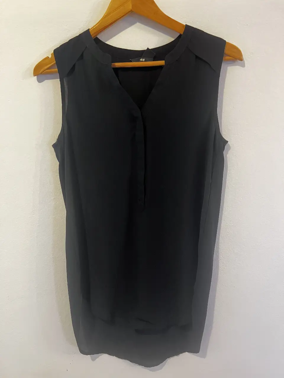 Blusa negra sin mangas de H&M, ideal para un look elegante y versátil. Confeccionada en un tejido ligero y fluido, perfecta para combinar con pantalones de vestir o faldas.