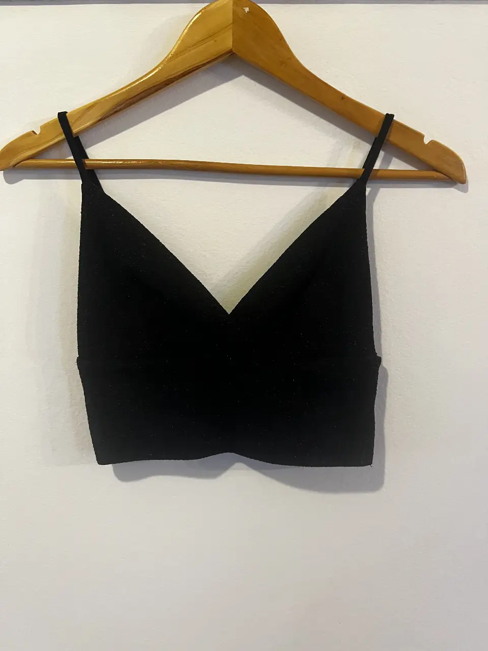 Top negro con escote en V y tiras finas. Ideal para combinar con jeans o faldas para un look casual y moderno.