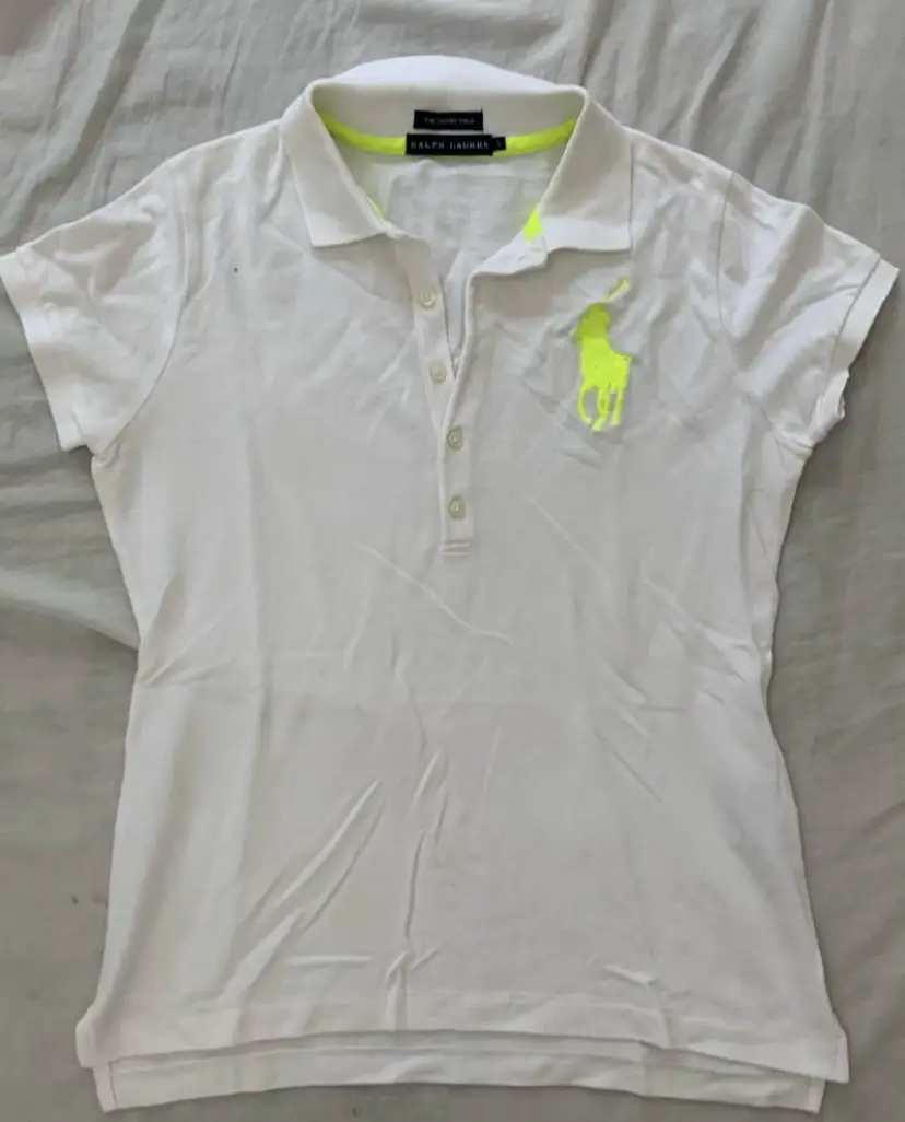 Remera polo blanca Ralph Lauren, con logo amarillo en el pecho. Talle S.  Medidas: axila a axila 50 cm; hombro a hombro 35 cm; largo 57 cm; ancho manga 22 cm