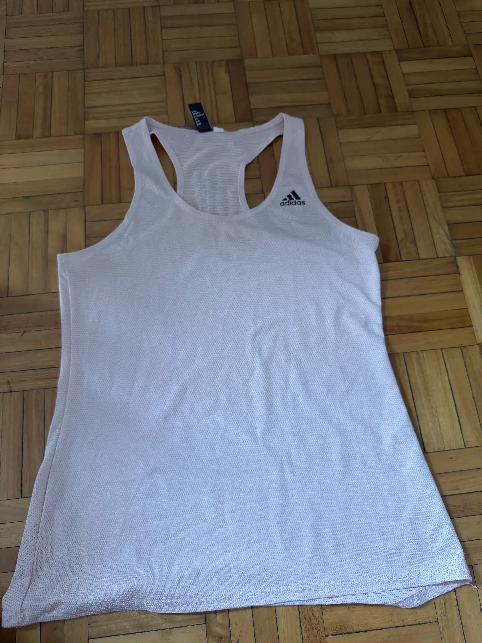 Musculosa deportiva Adidas rosa, ideal para entrenamientos. Confeccionada en tejido transpirable, ofrece comodidad y libertad de movimiento. Logo Adidas en el frente.
