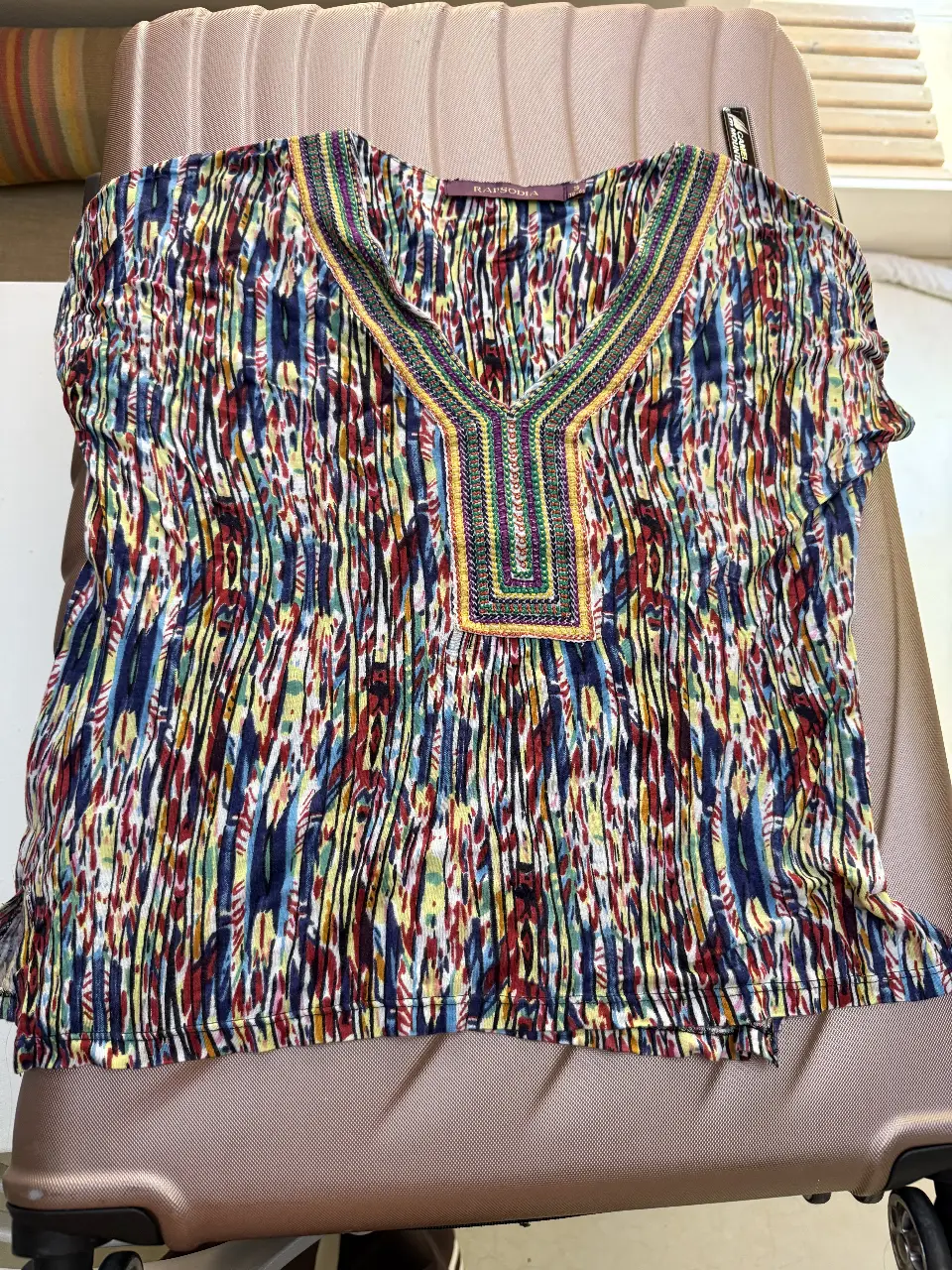 Blusa de mujer con estampado vibrante y cuello en V adornado. Ideal para un look casual con un toque bohemio.